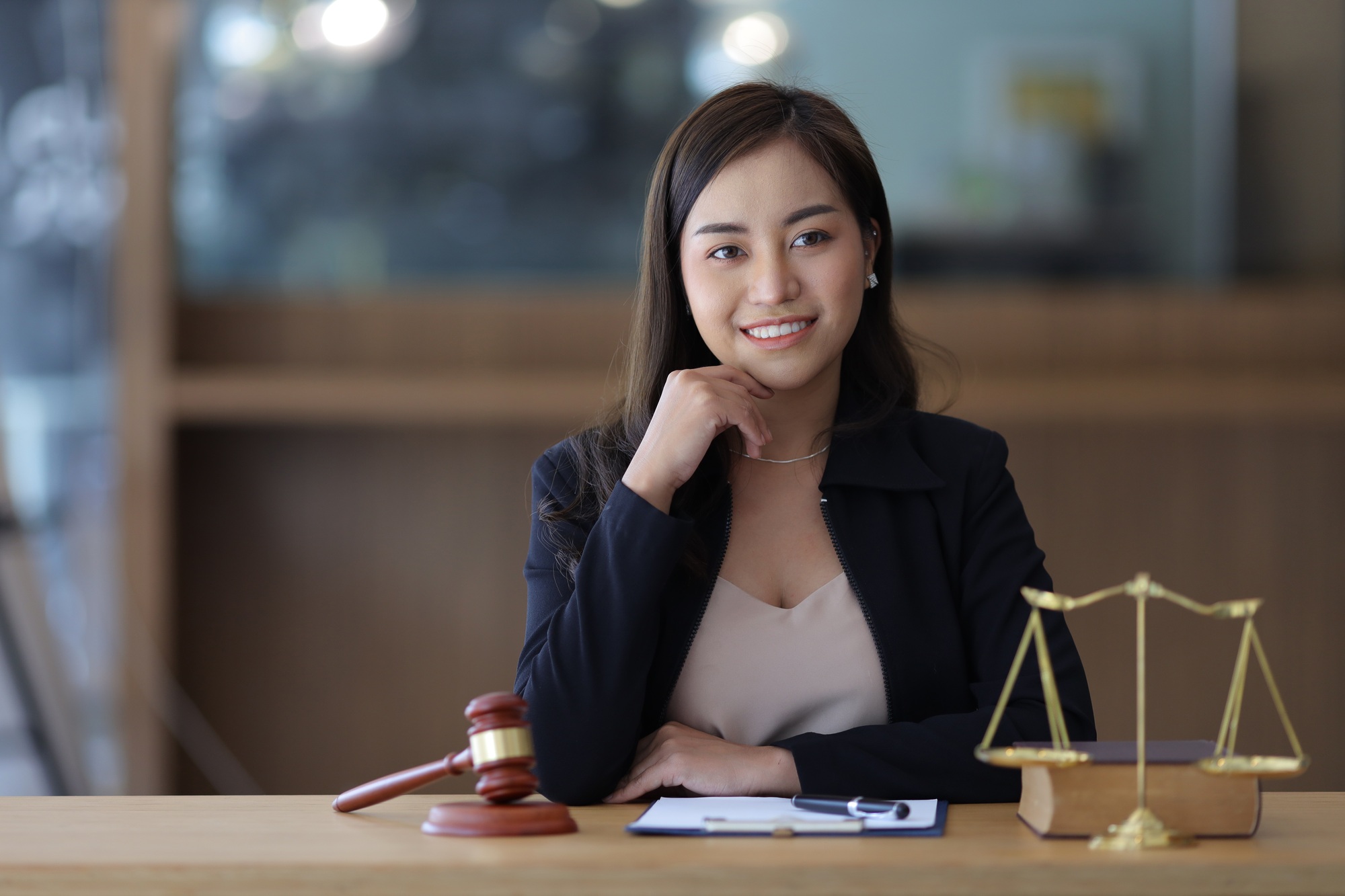 Portrait of a beautiful young woman lawyer sitting at a desk in a lawyer's office.