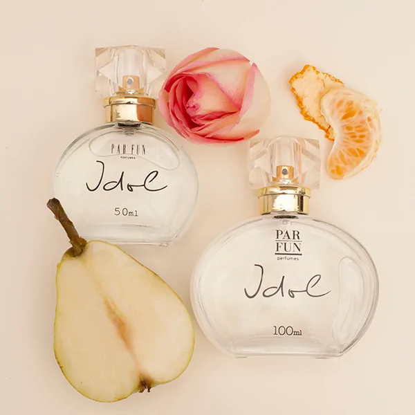 Dois frascos de perfume Idole ao lado de rosa, pera e tangerina