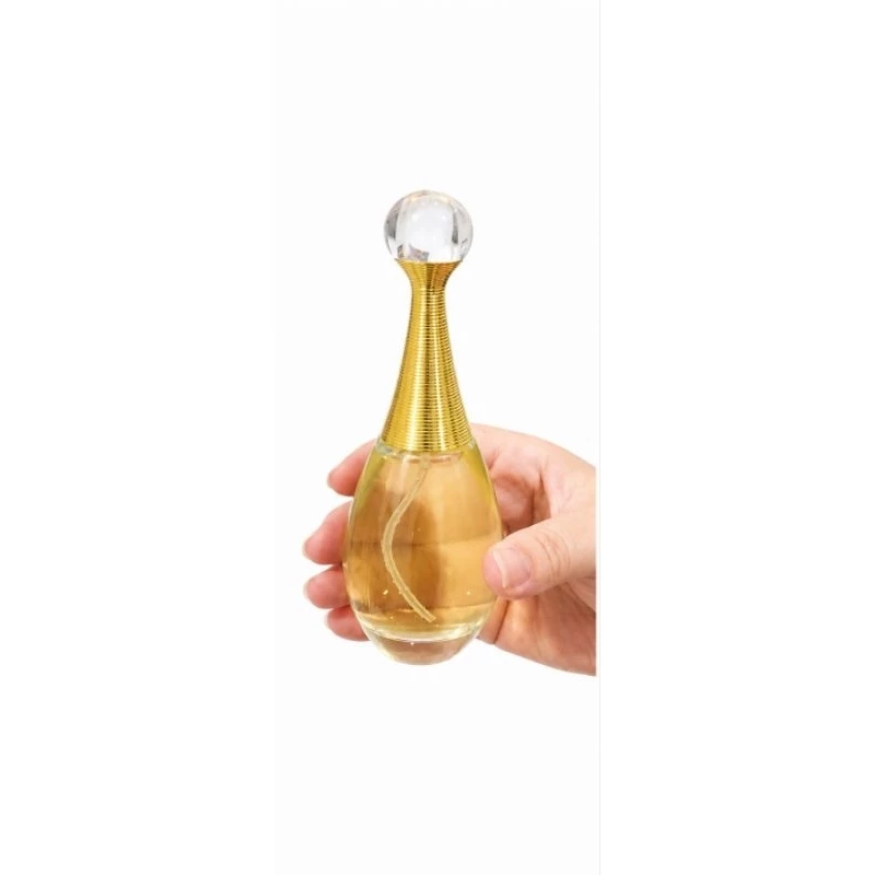 Frasco dourado de perfume Jasmim ao Entardecer sendo segurado na mão