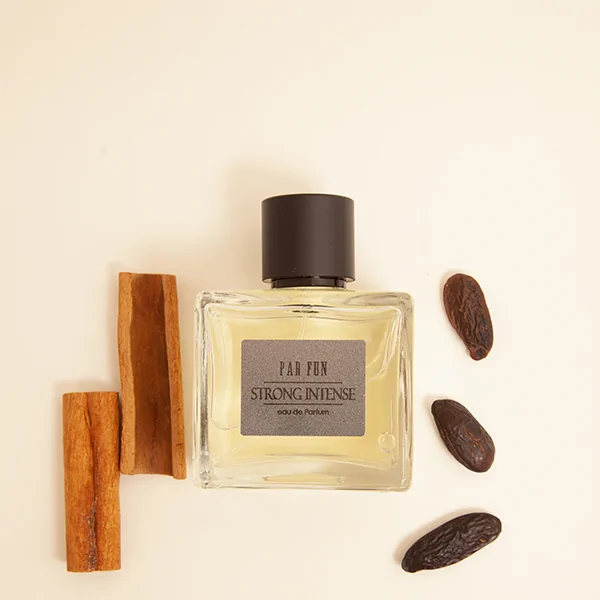 Frasco de perfume Strong Intense ao lado de canela e cacau
