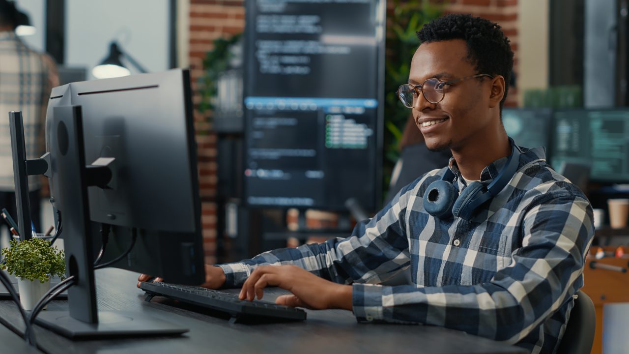 Elementor #156 2 portrait of software engineer writing code arranging glasses and being happy about parsing results e1698777675815